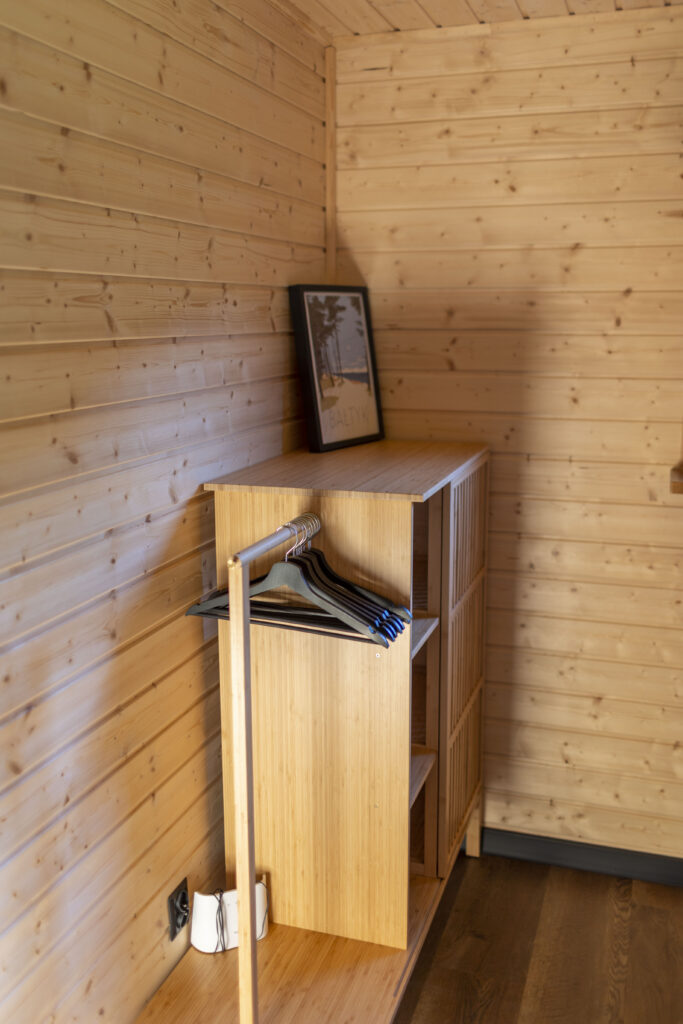 Półeczka z wieszakami na ubrania w sypialni.